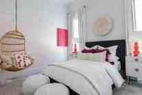 Electric orange lamps pair with the crisp white linens and pops of pink in this teen girl’s bedroom.