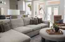 The nubby texture of the sofa and ottoman in beige, brown and taupe, provides a neutral backdrop for the African textiles in browns and the chunky ivory and chocolate tones of the area rug.