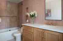 Paired with a salmon/blush tile, the natural stained vanity provides warmth and grounds this teen girl’s bathroom.